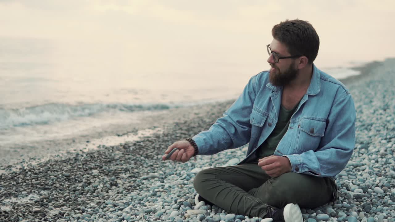 hombre sentado en la playa al atardecer