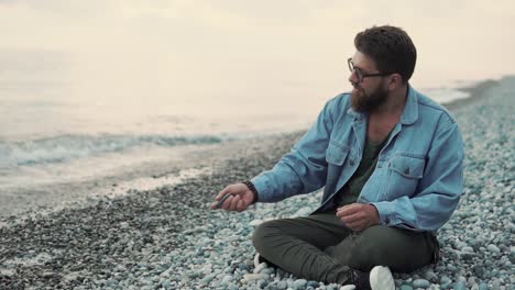 hombre sentado en la playa al atardecer