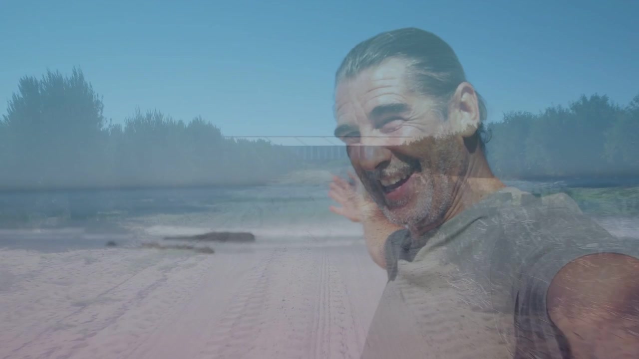 Hombre maduro desvaneciéndose en la playa, girando, sonriendo, presentando arena a través de una superposición transparente para viajes.