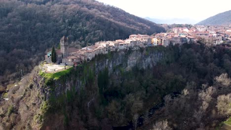 aerial drone pan of castellfollit de la roca: the cliffside town in girona’s pyrenees, near garrotxa volcanic zone