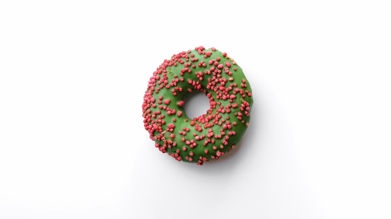 donut dulce rotativo y brillante con hielo verde aislado. filmado con la cámara de cine red raven 4k
