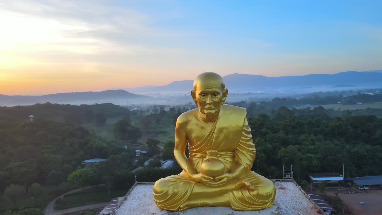 4k antena gran estatua de monje luang por tuad rodeada de montañas de khao yai al amanecer en tailandia