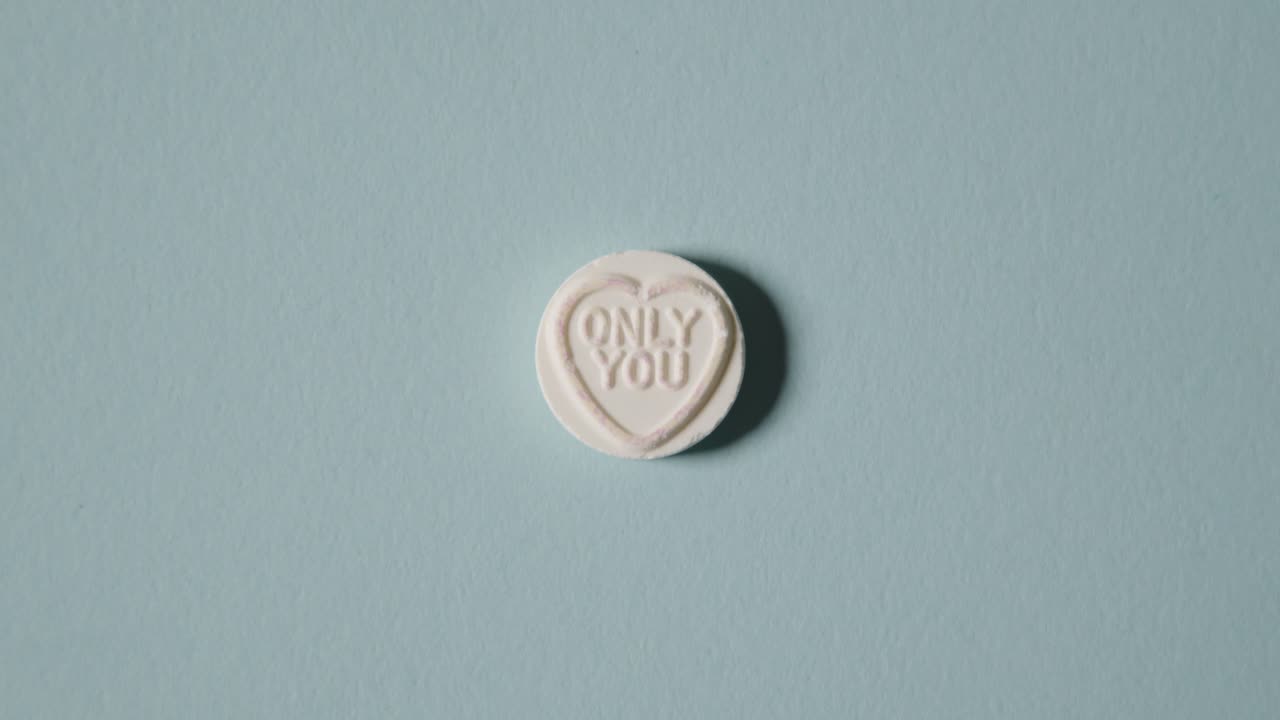 파란색 배경에 메시지만 있는 하트 사탕을 손에 들고