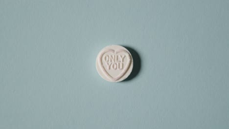 mano recogiendo caramelos de corazón con solo tu mensaje sobre fondo azul