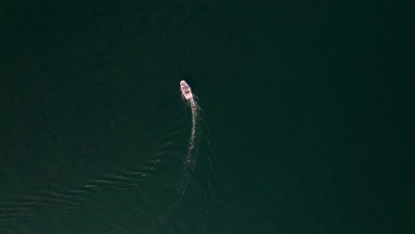 top down drone shot of a boat moving in the middle of a lake