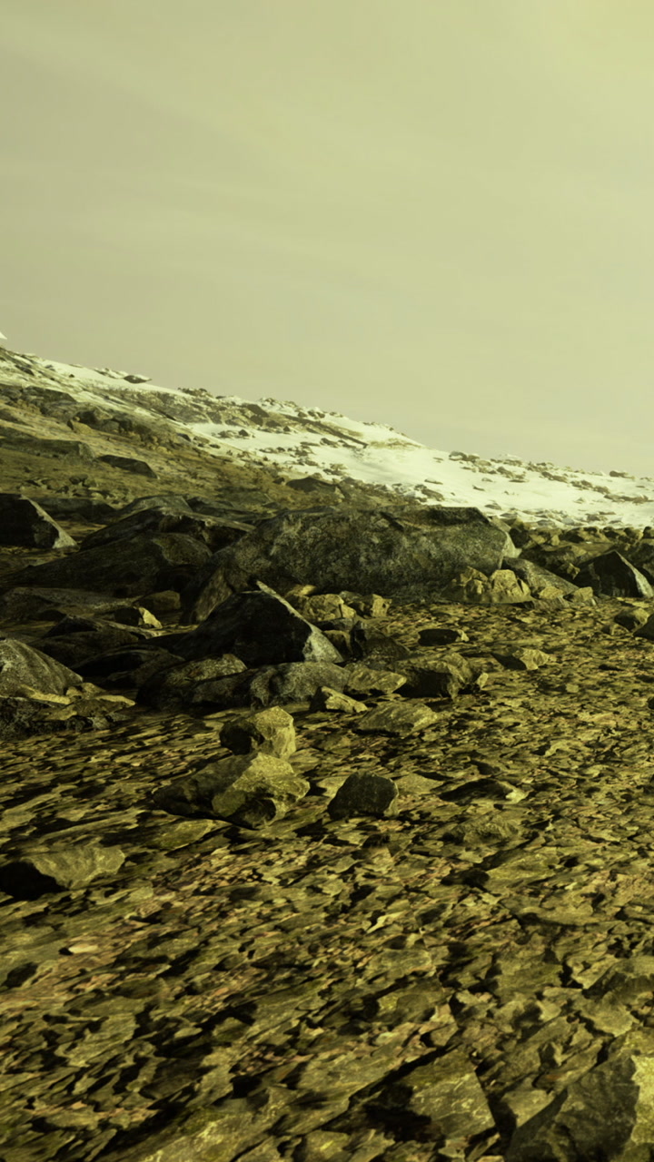 Rocky terrain with snow in a yellowish light at a distant mountain
