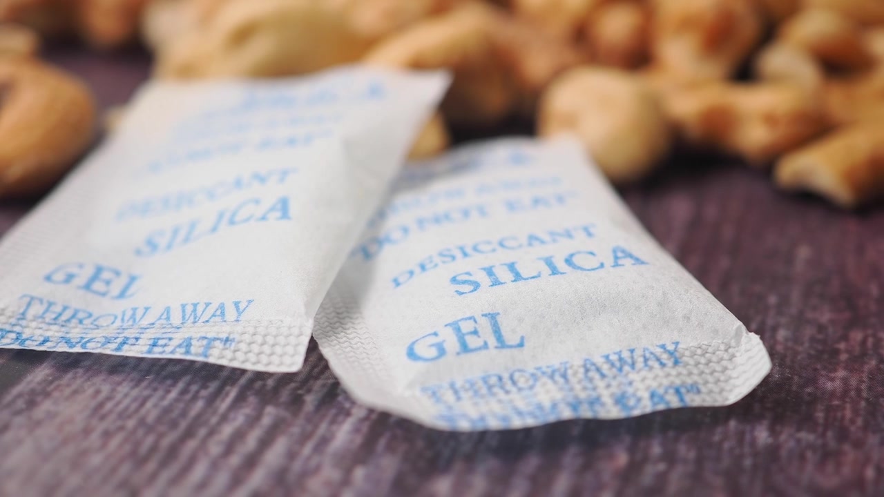 To silicagelpakker med cashewnødder i baggrunden