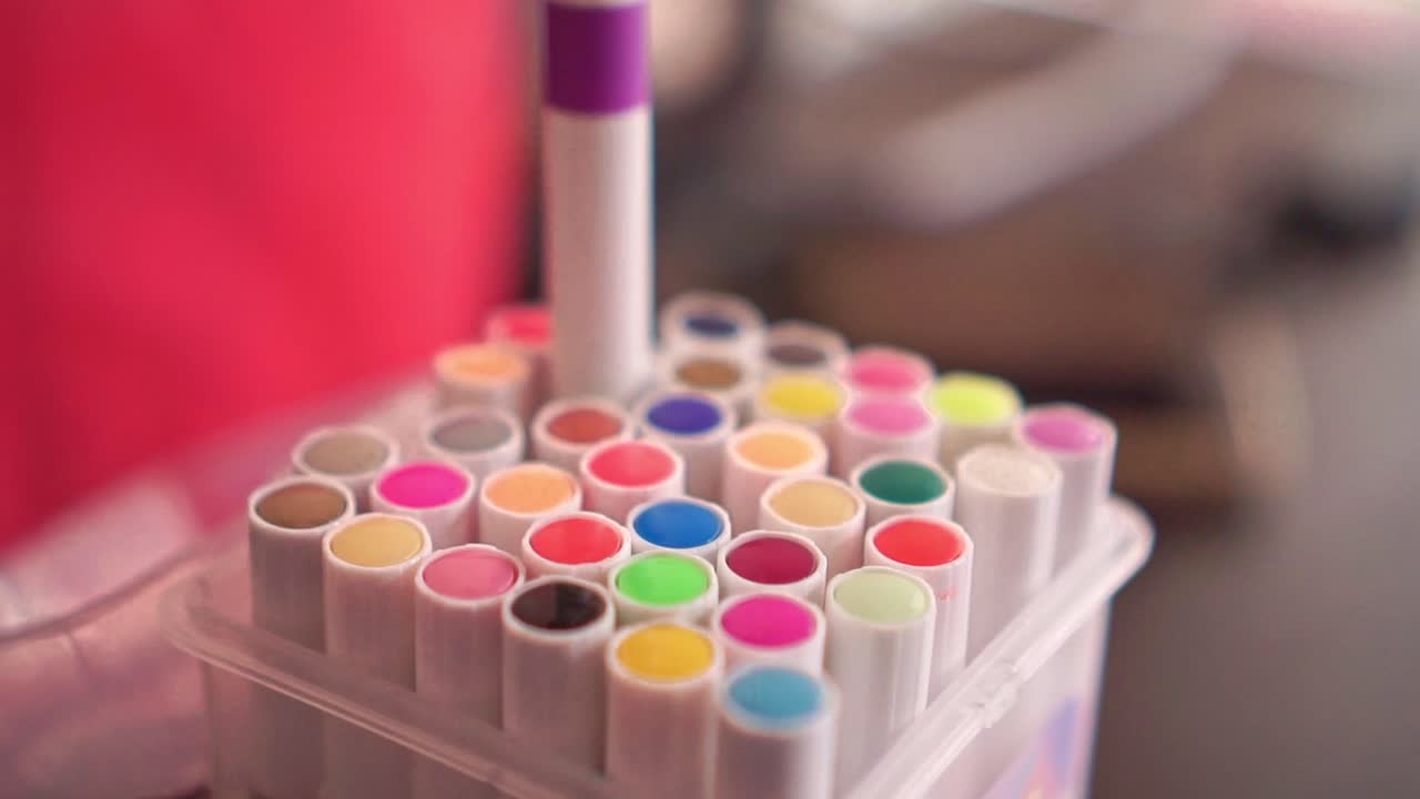 Mano che prende un pennarello colorato da un supporto, spazio di lavoro creativo, materiali per l'arte, cancelleria vivace, strumenti per disegnare e concetto di creatività fai-da-te