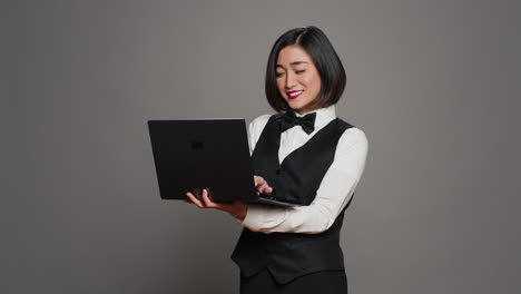 asian hotel employee registering people using laptop at front desk