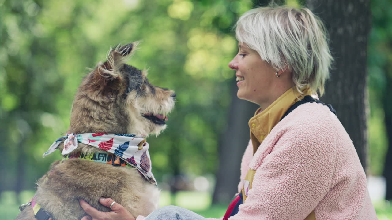 Young Woman Petting Happy Dog while Sitting Together in Park