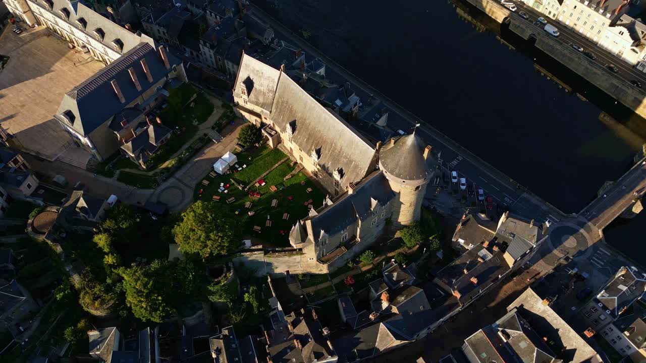 Drone orbits Laval Castle in Mayenne at golden hour with river, houses, and birds visible