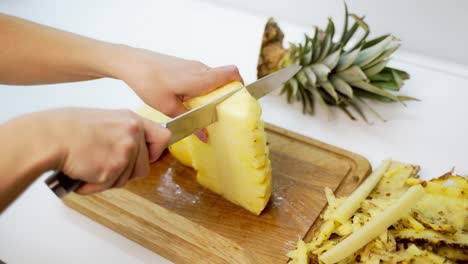 woman cutting pineapple. fresh pineapple on the cutting board. hands of a female preparing exotic fruit for guests. close-up.