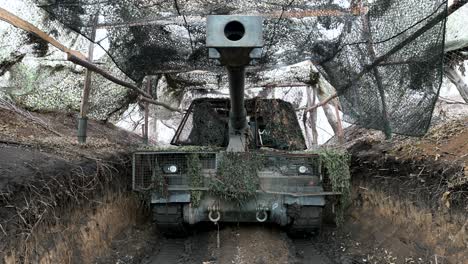 a ukrainian pzh 2000 howitzer sits in a camouflaged firing position. this view shows a key player in the long-range artillery duels that define much of the war in ukraine