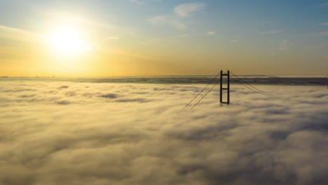 aerial reveal of the humber bridge as the sun is rising with low cloud and fog passing by very quickly