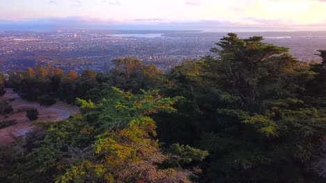 Unglaublicher-Sonnenuntergang-Mit-Natürlichem-Wald-Und-Stadt-Unten-Im-Tal,-Brillante-Sonnenuntergangsfarben-Und--tiefe