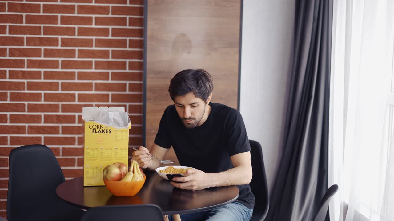 el hombre desayuna y usa el teléfono inteligente en casa