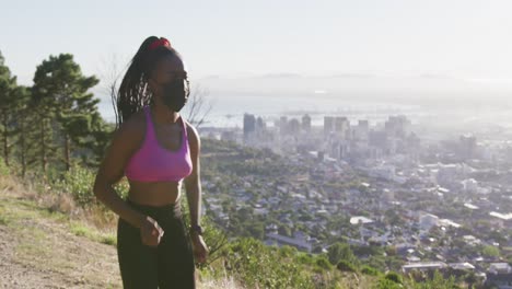 mujer afroamericana con máscara facial corriendo al aire libre