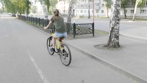 young woman riding a bicycle in cloudy weather near the sea on wooden embankment