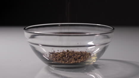 Slow-motion-shot-of-some-coffee-grains-being-poured-into-a-small-glass-bowl