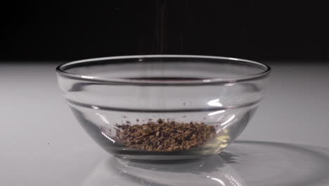 slow-motion shot of some coffee grains being poured into a small glass bowl