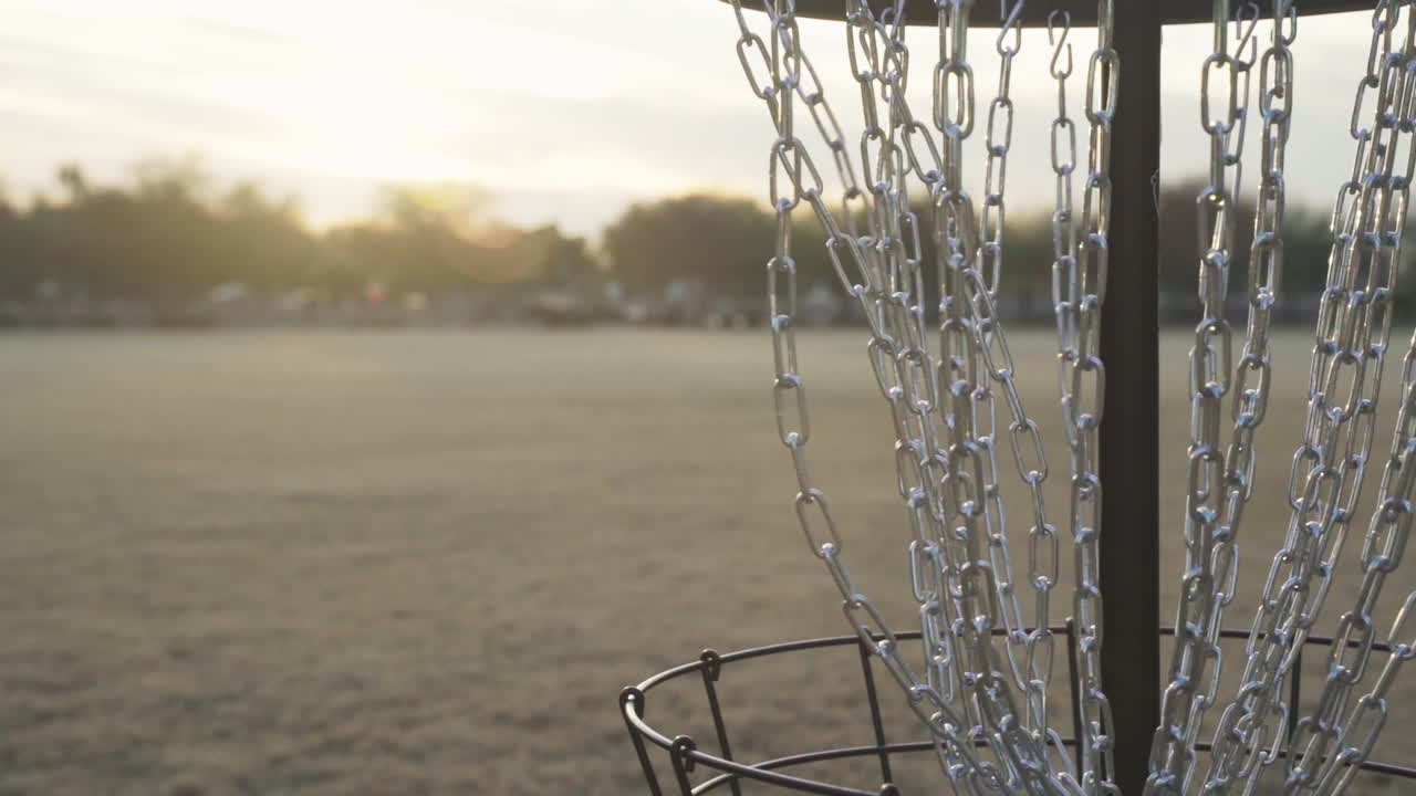 Disc Golf Putt Made into the Center Chains of a Frolf Basket during a Beautiful Sunset