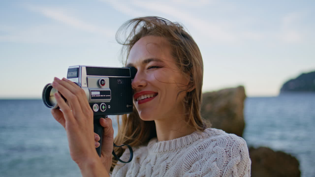 Woman shooting seascape camera standing windy ocean shore closeup. Smiling lady