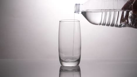 pouring water into a glass from a plastic bottle