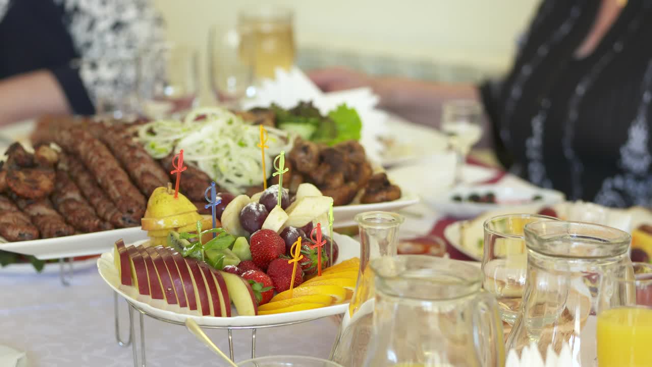 mesa de cena festiva con una deliciosa comida lula kebab y plato de frutas.