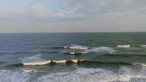 Drone-shot-over-a-beach-and-Atlantic-ocean-waves,-hazy-sunrise-in-Brigantine,-USA