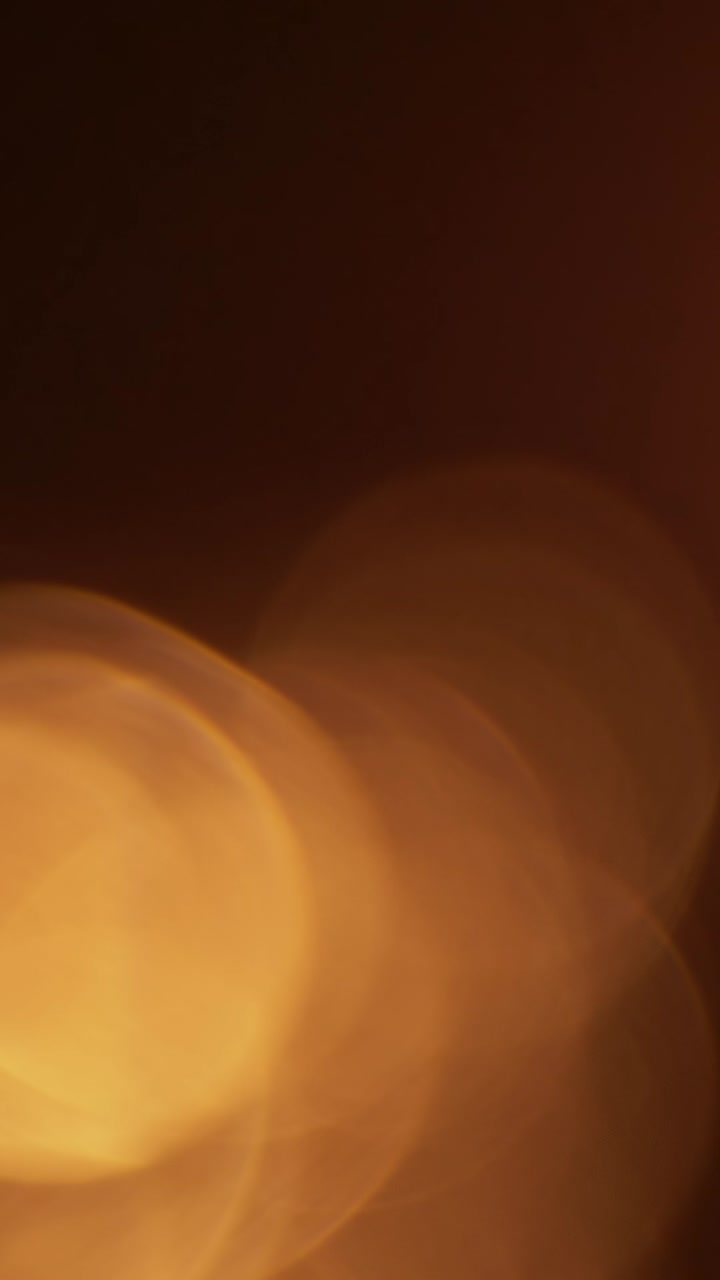 Effetti di luce bokeh caldi in transizione su sfondo scuro.