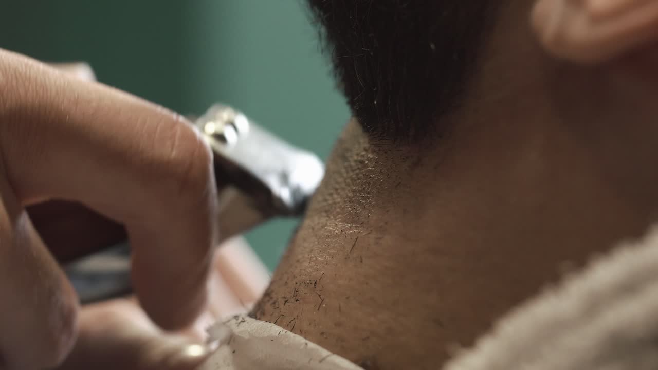 Primo piano di un barbiere che rade il collo di un cliente con un rasoio elettrico