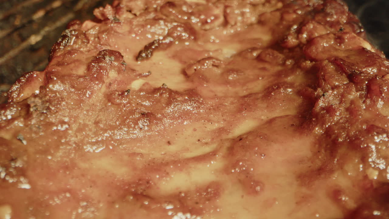 Extreme close up of a slab of spareribs slowly being grilled on a barbecue