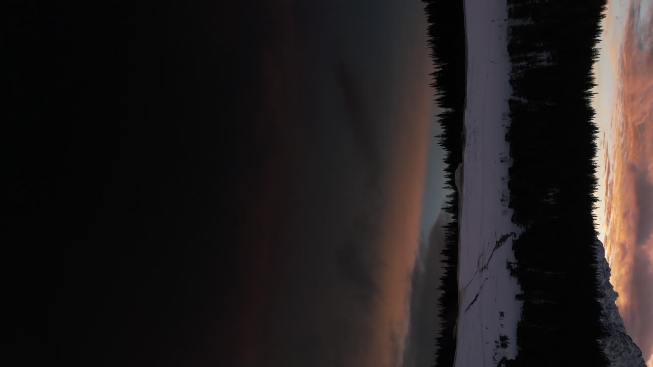 Colorful cloudy sky reflecting on Pal&ugrave; lake at sunset in winter season, Valmalenco in Italy