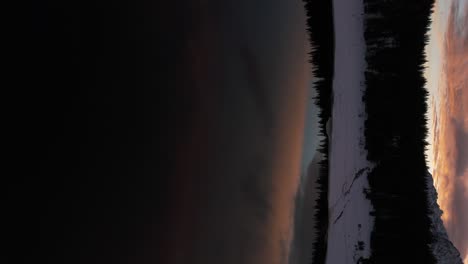 Colorful-cloudy-sky-reflecting-on-Palù-lake-at-sunset-in-winter-season,-Valmalenco-in-Italy