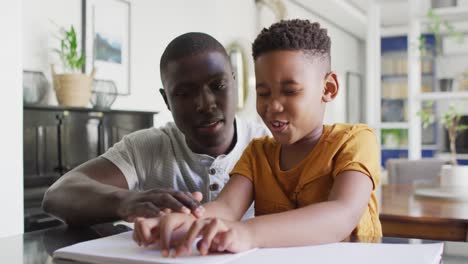 Video-Eines-Afroamerikanischen-Vaters,-Der-Seinem-Blinden-Sohn-Beim-Lesen-In-Blindenschrift-Hilft
