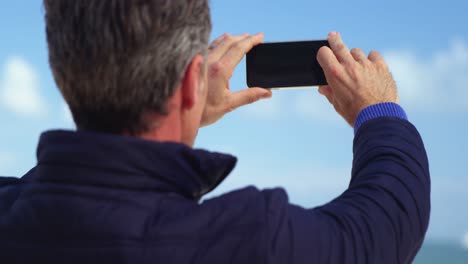 hombre maduro tomando una foto de la vista desde un teléfono móvil
