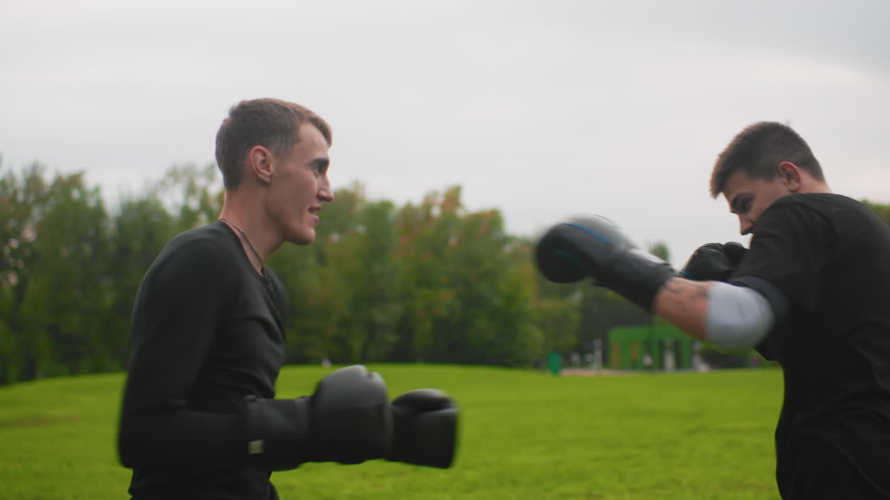 white men sparring outdoors on grass, disciplined mitt work and focused exchanges between amateur boxers slow controlled jabs, defensive blocks, stance adjustments and coachlike guidance