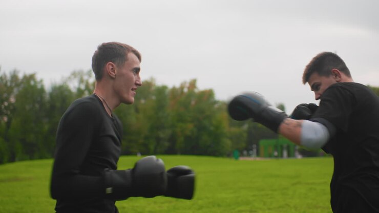 white men sparring outdoors on grass, disciplined mitt work and focused exchanges between amateur boxers slow controlled jabs, defensive blocks, stance adjustments and coachlike guidance
