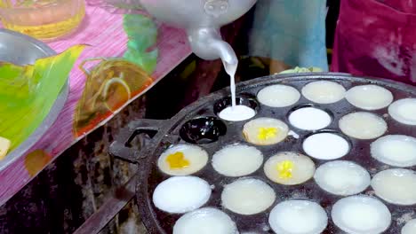 close-up of batter being poured into a hot plate to make mini pancakes.
