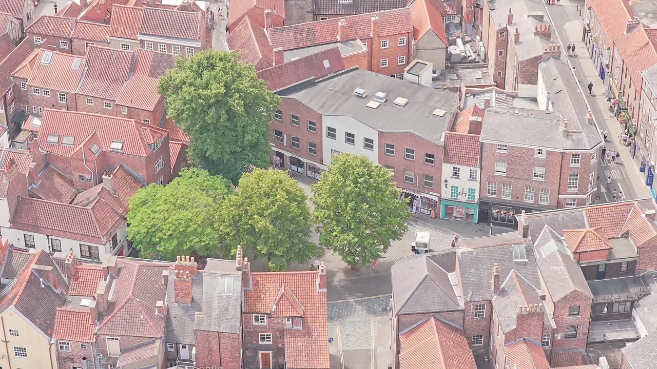 Close aerial view shopping area of The Shambles, York, England, lively streets, green trees, red rooftops, vibrant tourism hub in summer