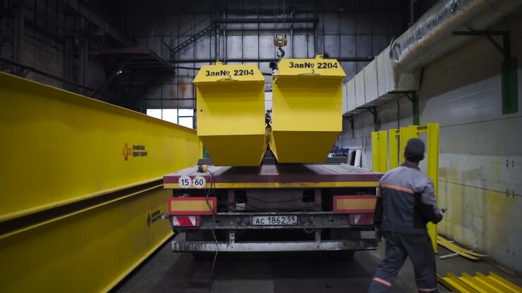 Loading heavy equipment on a truck in a factory setting