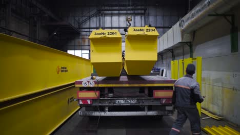 loading heavy equipment on a truck in a factory setting