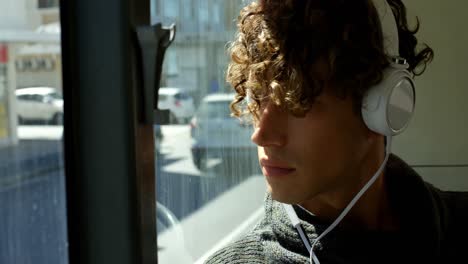 male commuter listening music on headphones while travelling in bus 4k