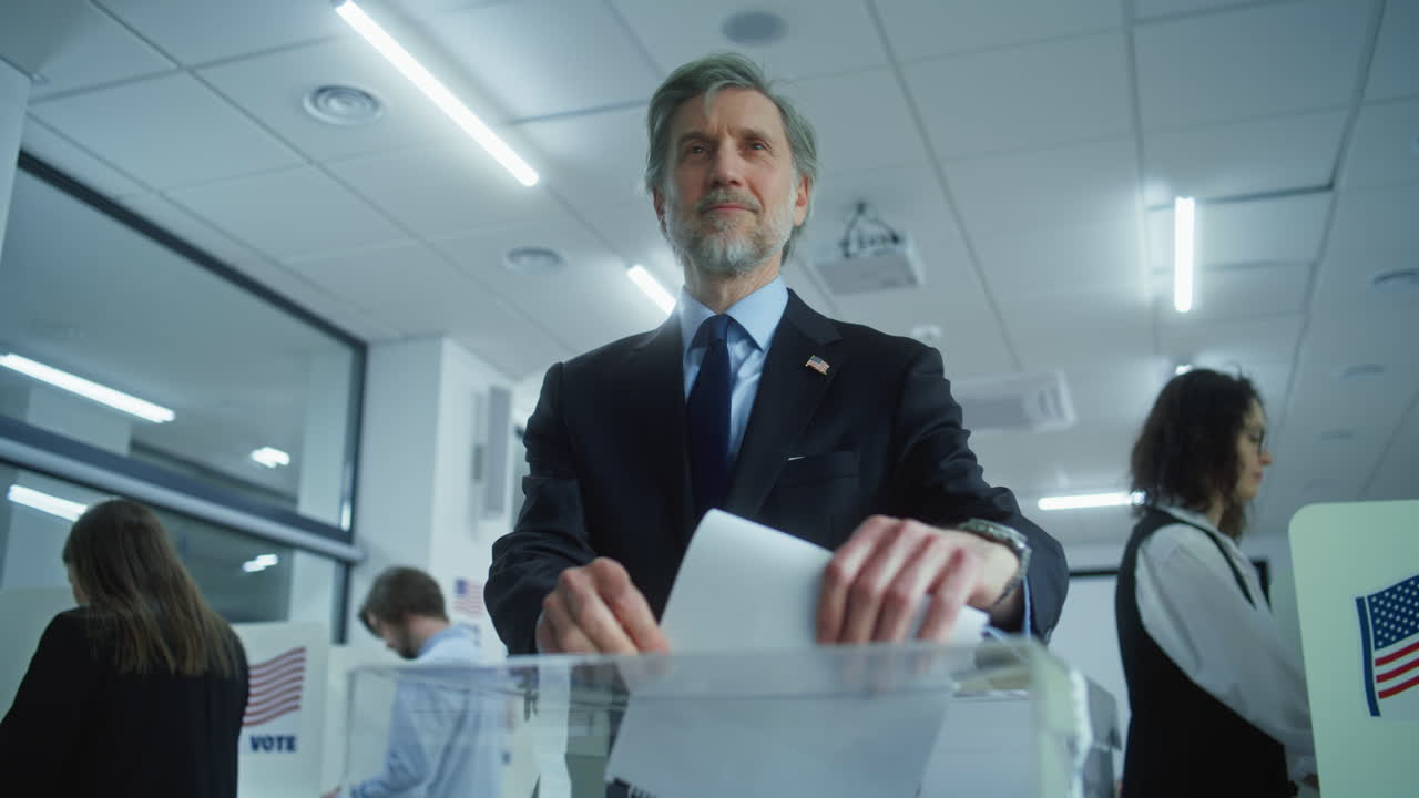 Mature us Businessman or Politician Puts Ballot in Box after Voting Mature us Businessman or Politician Puts Ballot in Box Press Takes Photo of Man after Voting Diverse American People Vote in Booths at Polling Station Elections Day in the United States of America