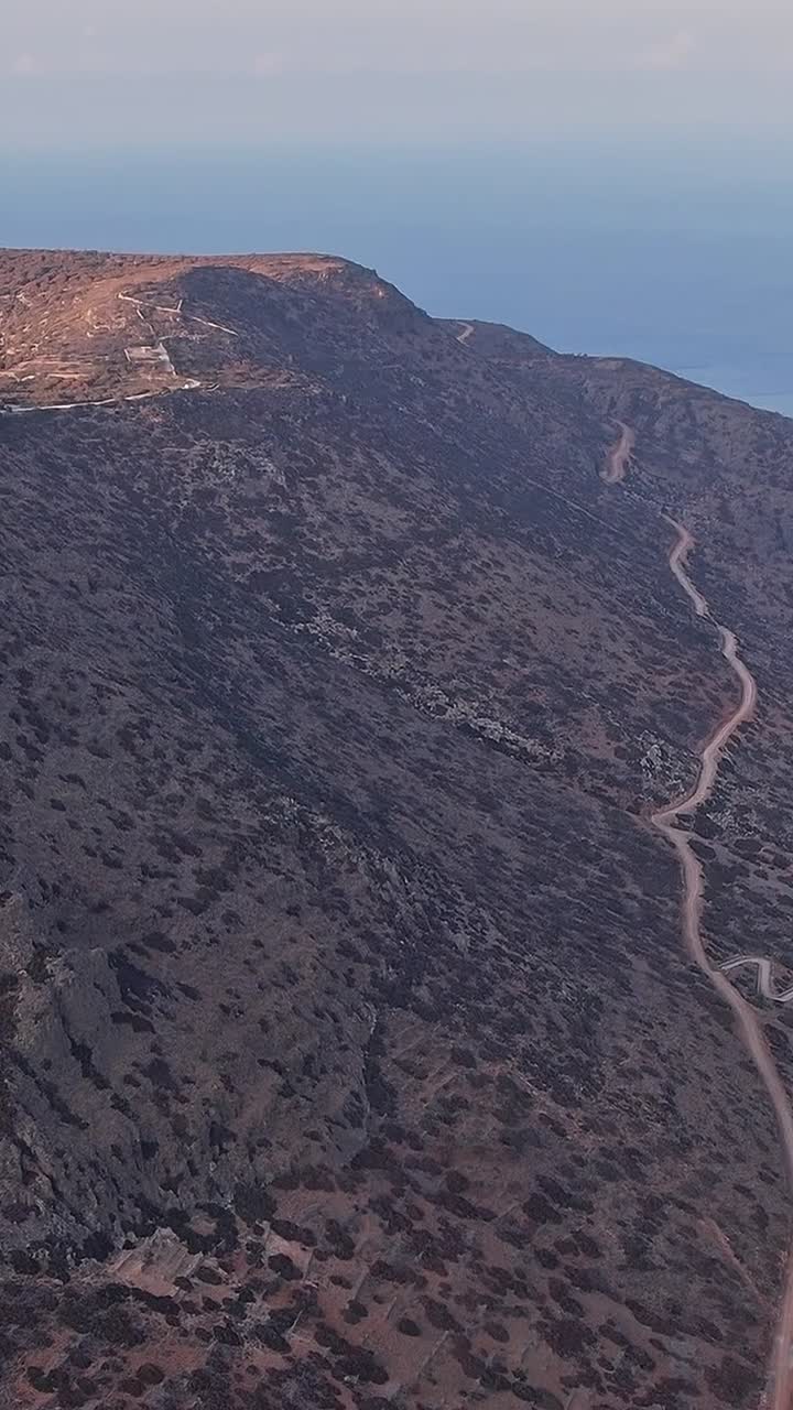 Vista aerea di una strada di montagna tortuosa con turbine eoliche e mare