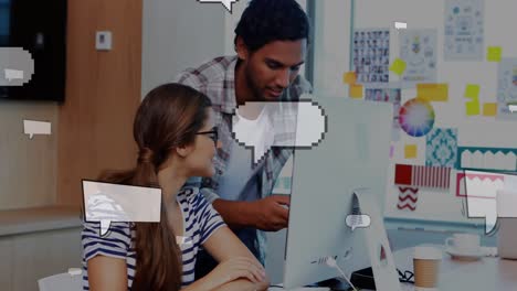 Animation-of-floating-speech-bubbles-over-multiracial-coworkers-discussing-over-desktop-in-office