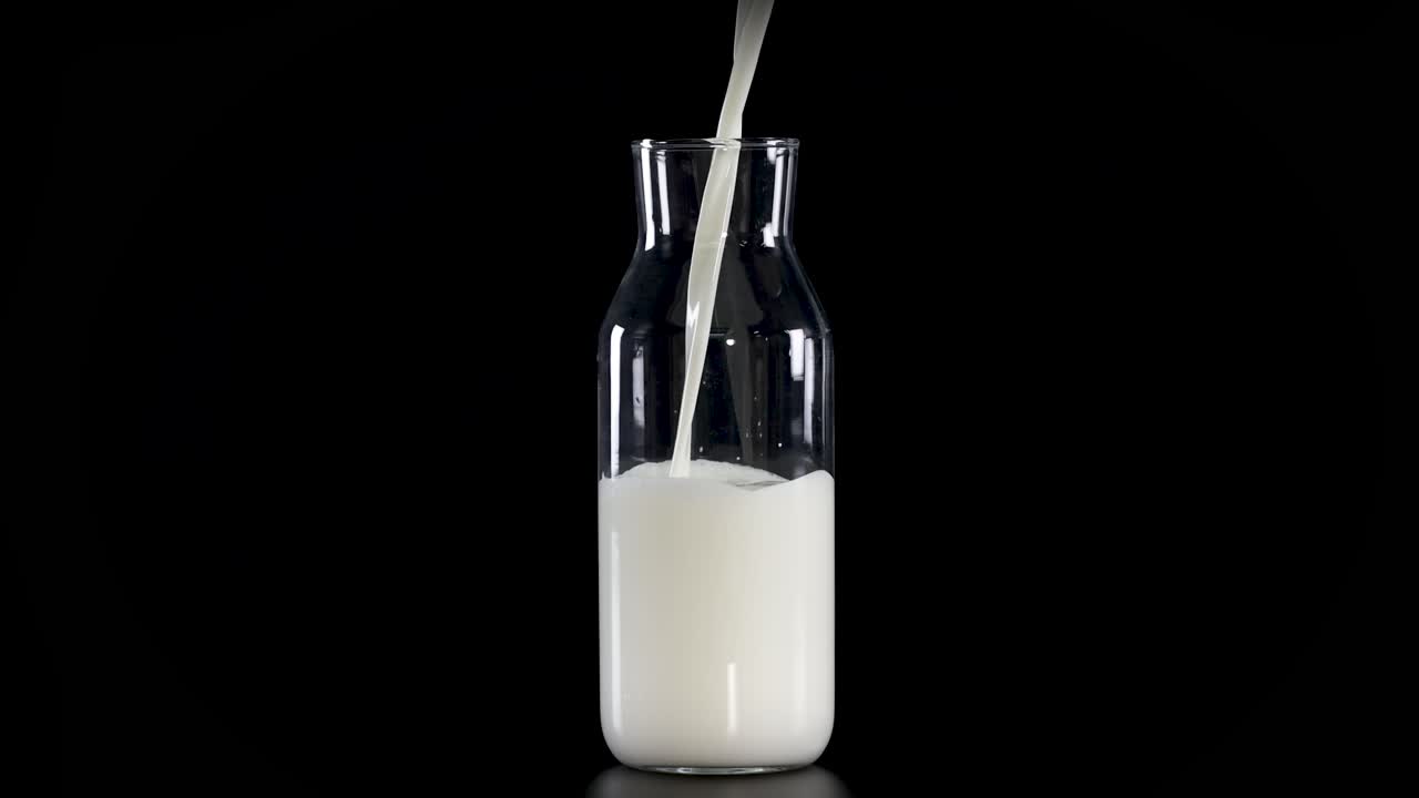 Milk being poured into a glass bottle