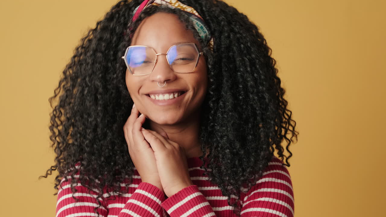 Happy Young Woman with Curly Hair and Glasses Smiling at Camera