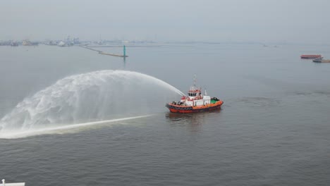 un barco realiza un saludo de agua rociando agua de sus extintores de fuego en el aire