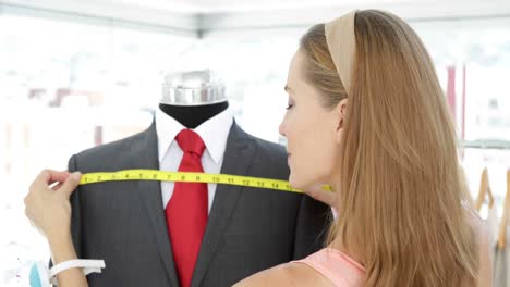 Attractive-fashion-designer-measuring-suit-on-mannequin